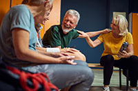 Group of four people in gym locker room, senior man and women talking after workout. Health, lifestyle, senior life concept.