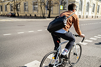 A cyclist with a briefcase rides a bicycle in the city to work.